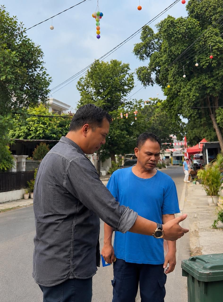 Pengurus yayasan berdiskusi dengan warga di jalan permukiman, di samping tempat sampah hijau